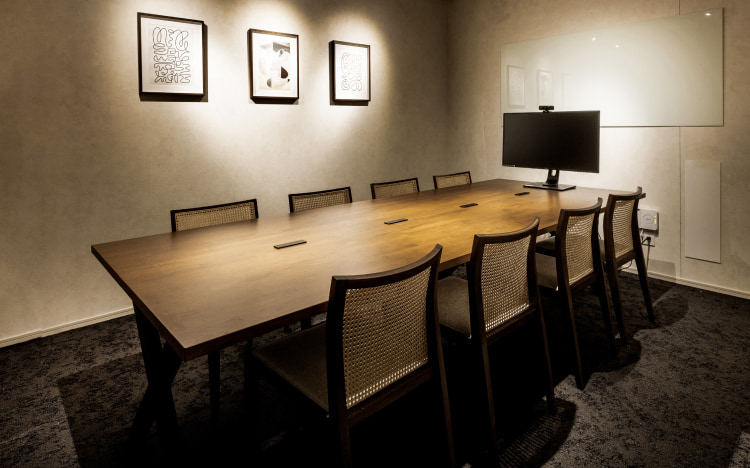 アートが飾られた壁と木製テーブルが印象的な、落ち着いた雰囲気の会議室